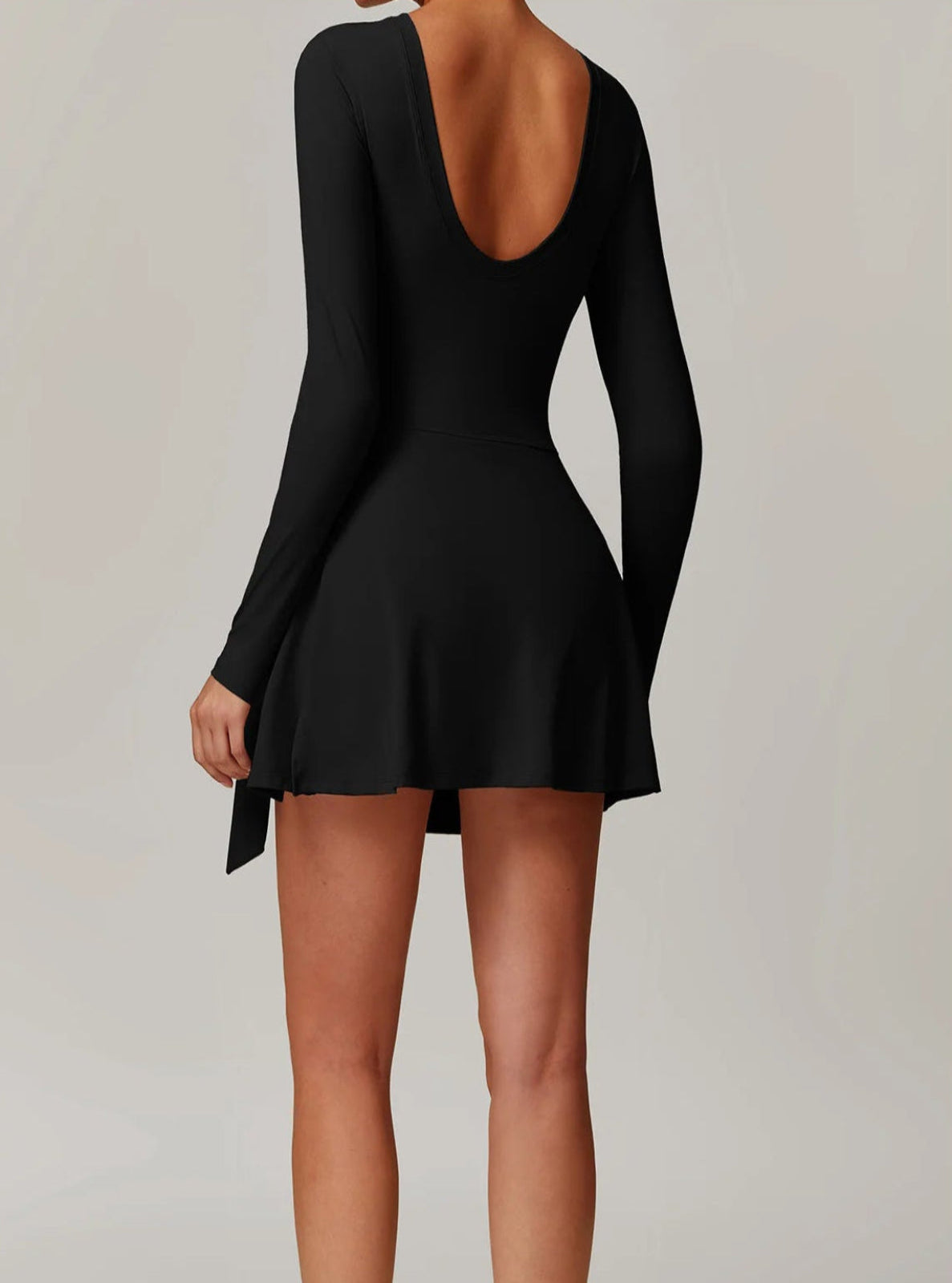 Person wearing a black dress with long sleeves on a plain background