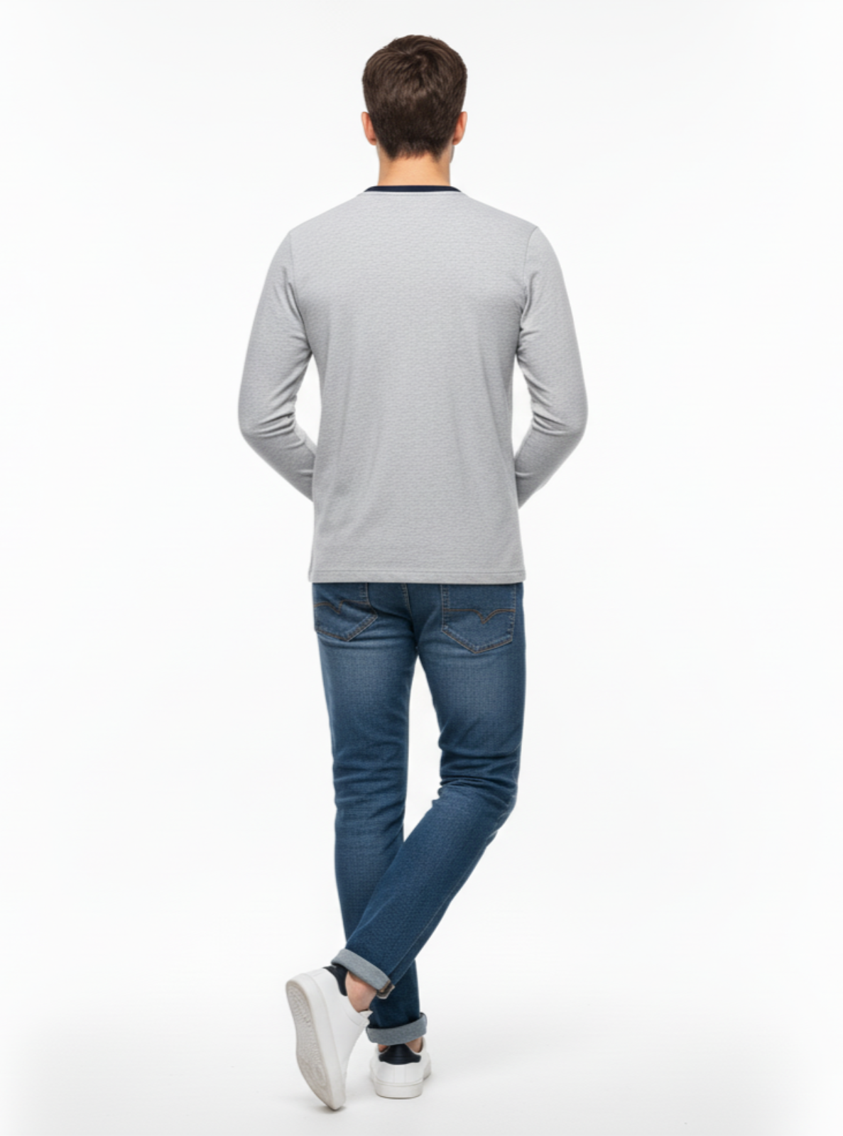 Man wearing a gray long-sleeve shirt and blue jeans on a white background