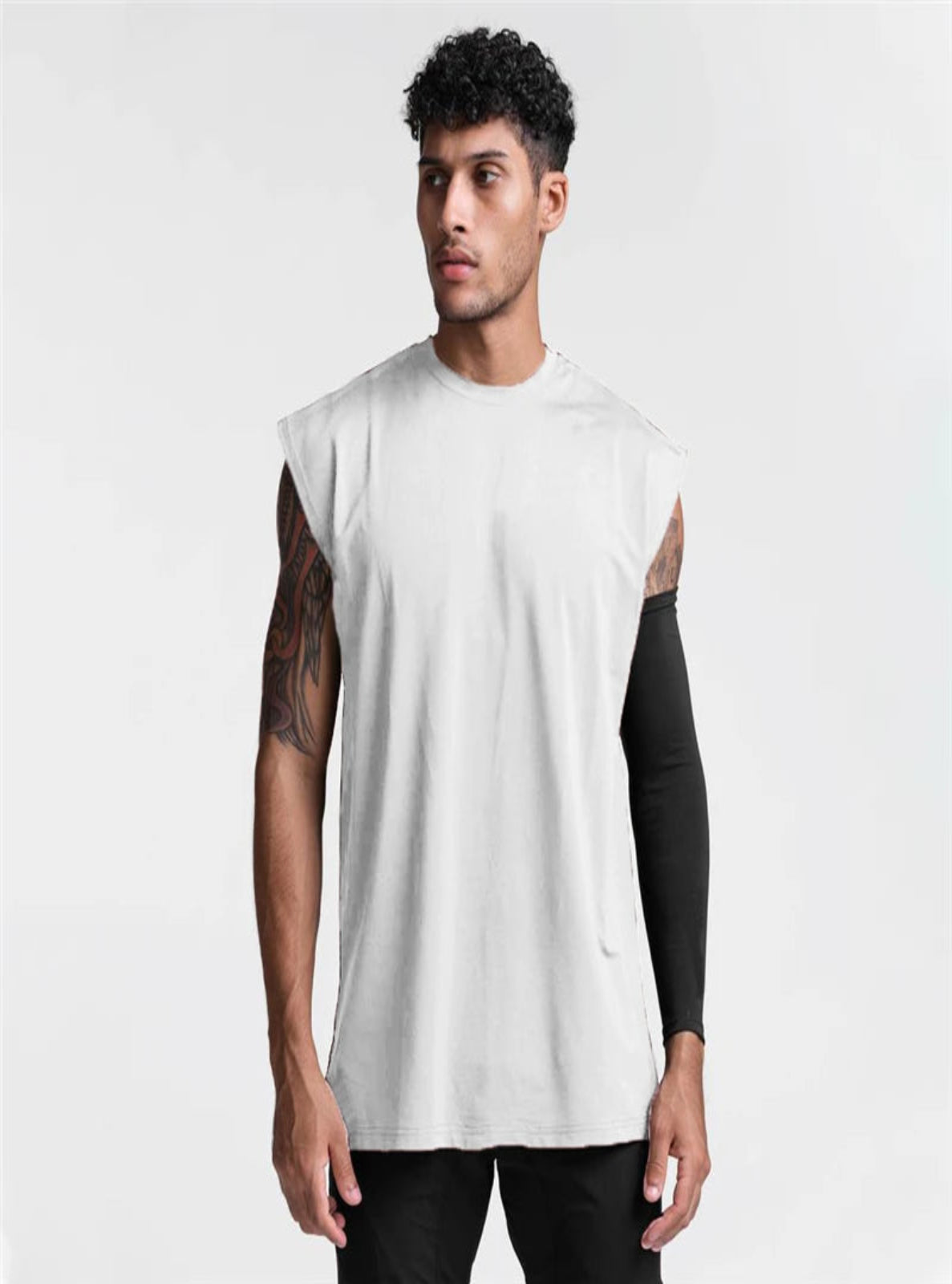 Man wearing a sleeveless white shirt with black arm sleeves on a plain background