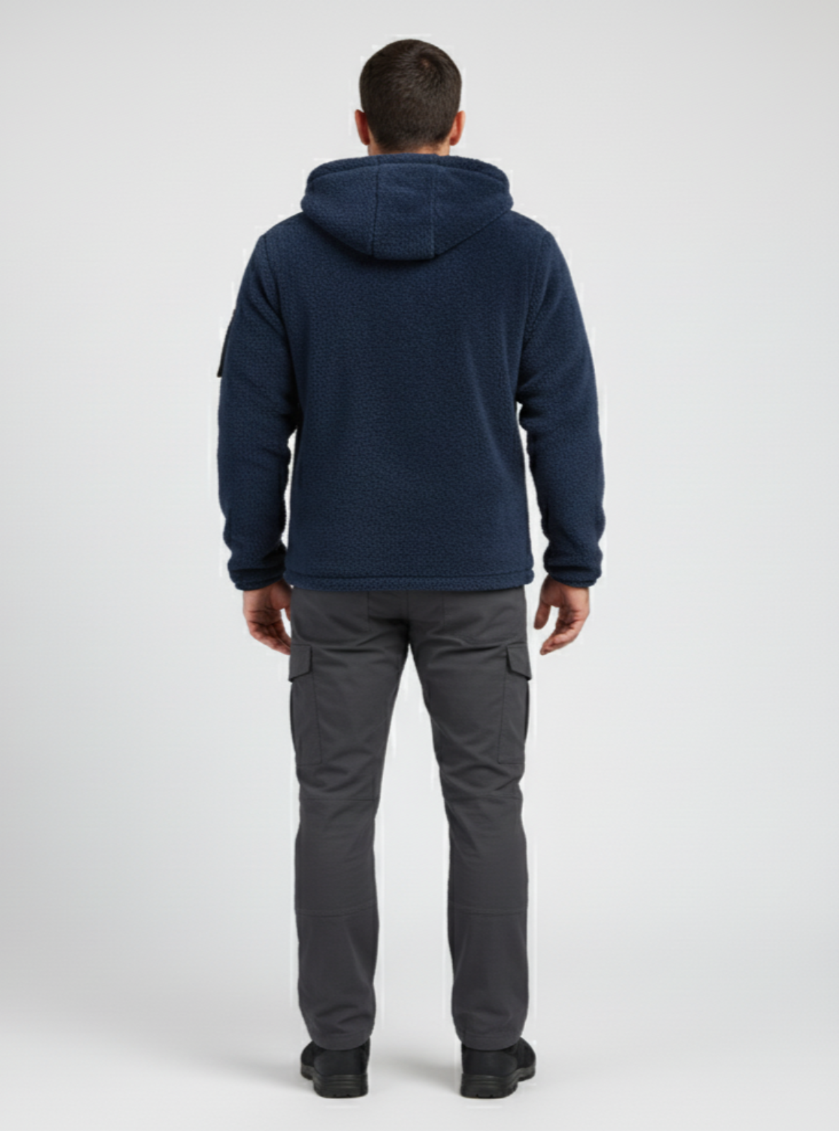 Person wearing a navy hoodie and gray pants on a white background