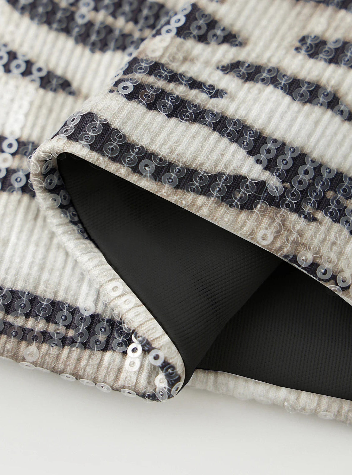 Close-up of a black and white patterned fabric with sequins on a white background