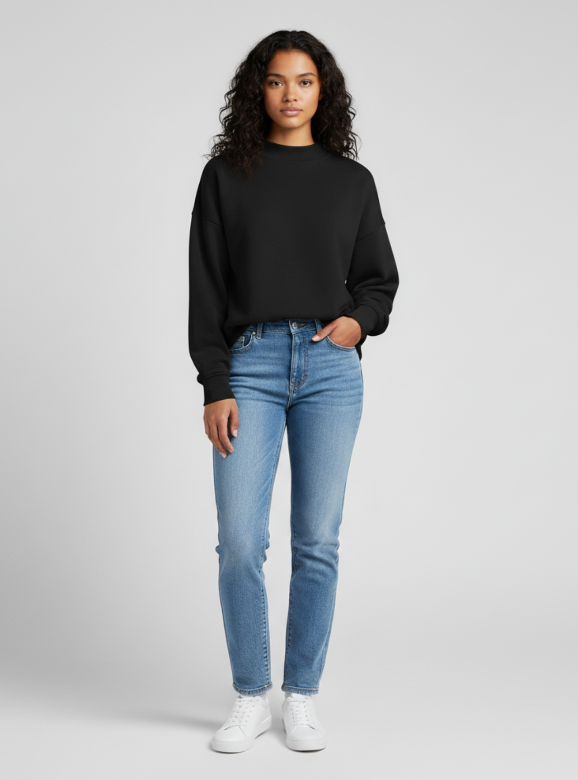 Woman wearing a black sweatshirt and blue jeans on a white background
