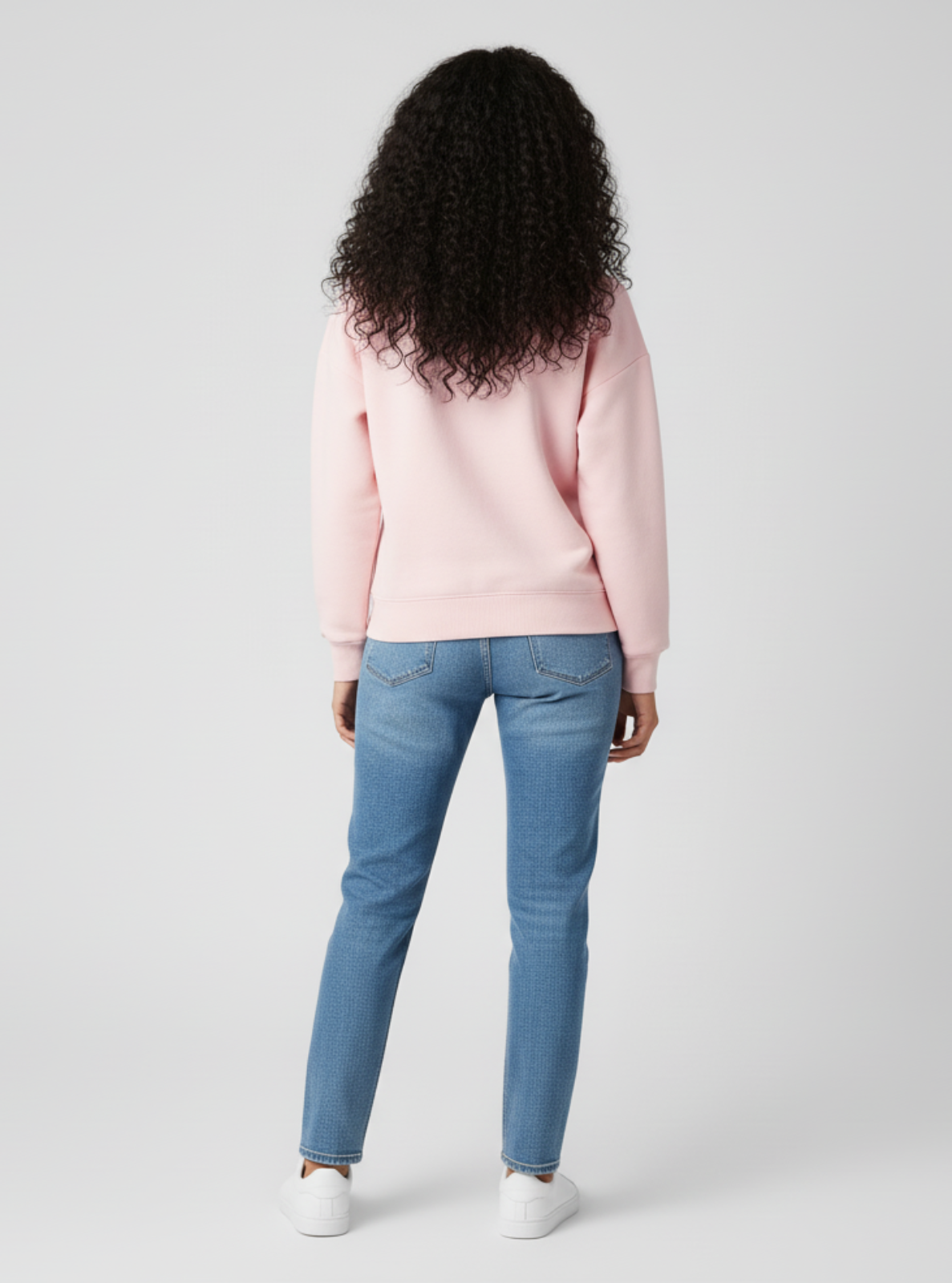 Person wearing a pink sweater and blue jeans on a white background