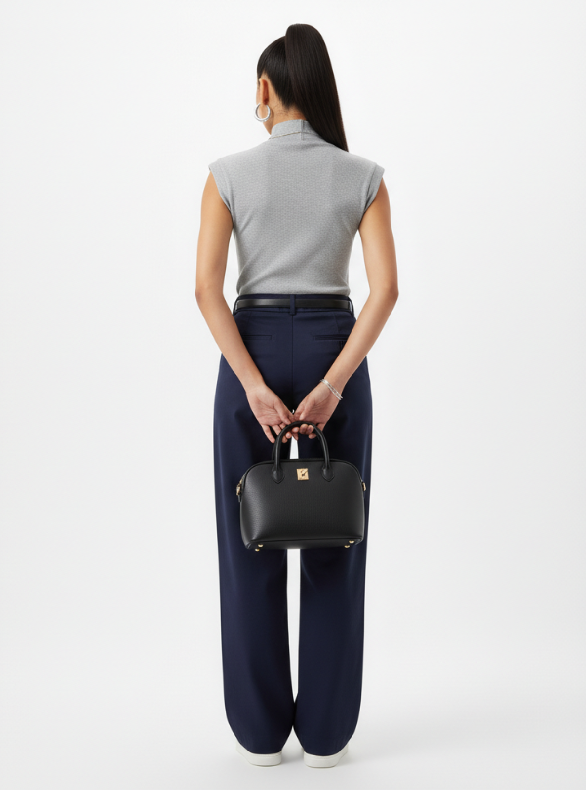 Person holding a black handbag against a white background
