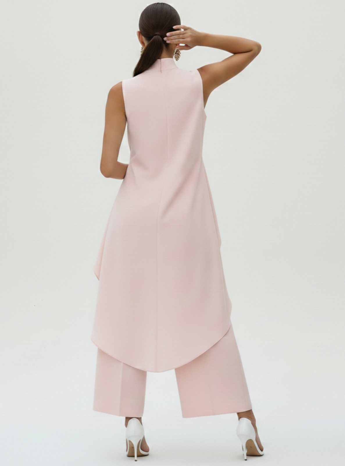 Woman wearing a pink sleeveless dress with a plain background