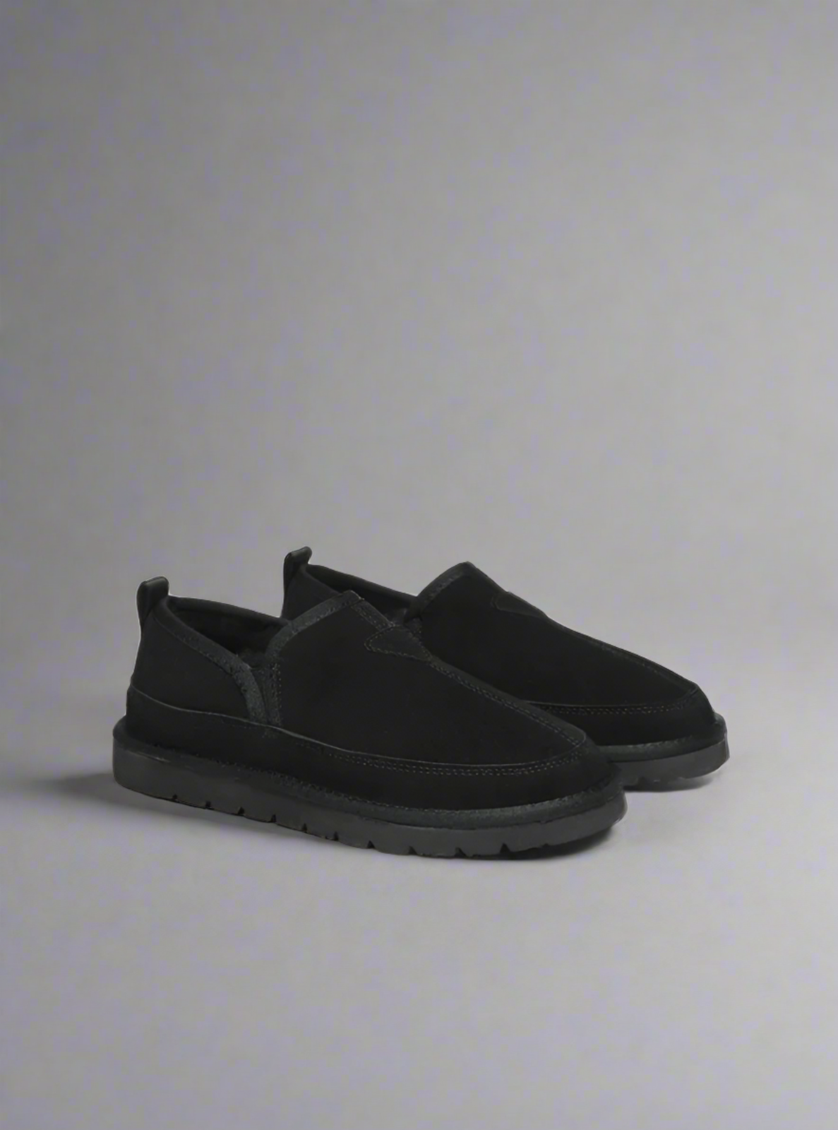 Black slip-on shoes on a light gray background
