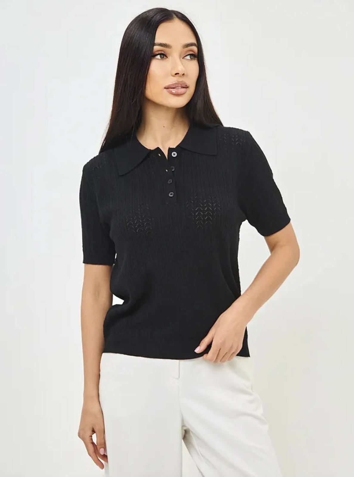 Woman wearing a black knitted polo shirt against a white background