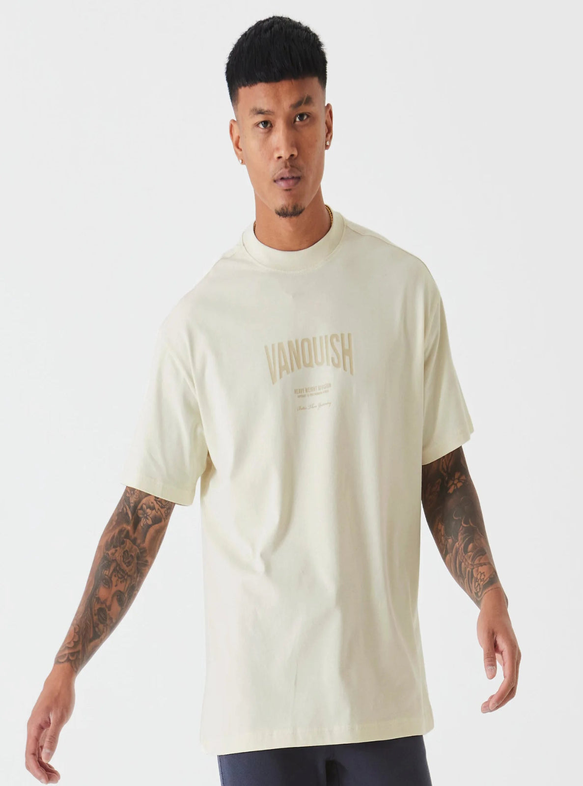 Man wearing a beige t-shirt with 'Vanquish' logo on a white background