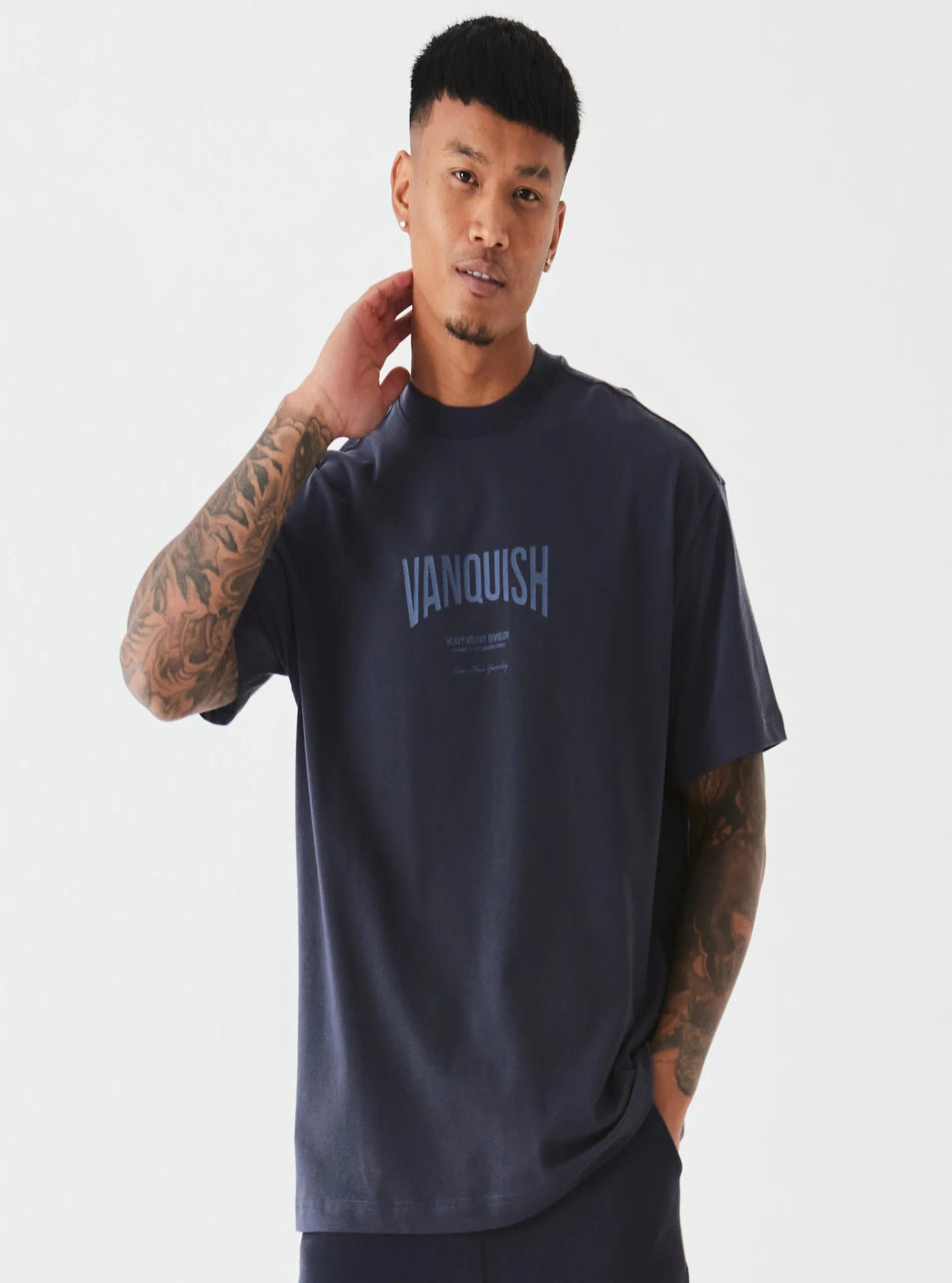 Man wearing a navy 'Vanquish' t-shirt on a white background