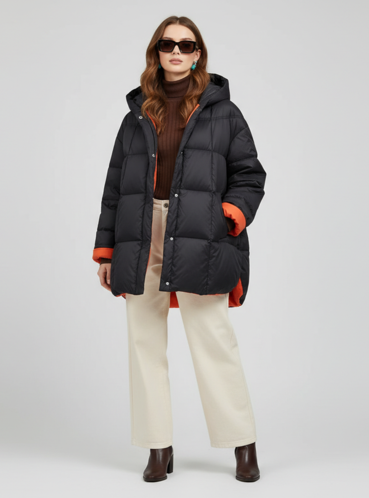 Woman wearing a black puffer coat with orange accents on a white background