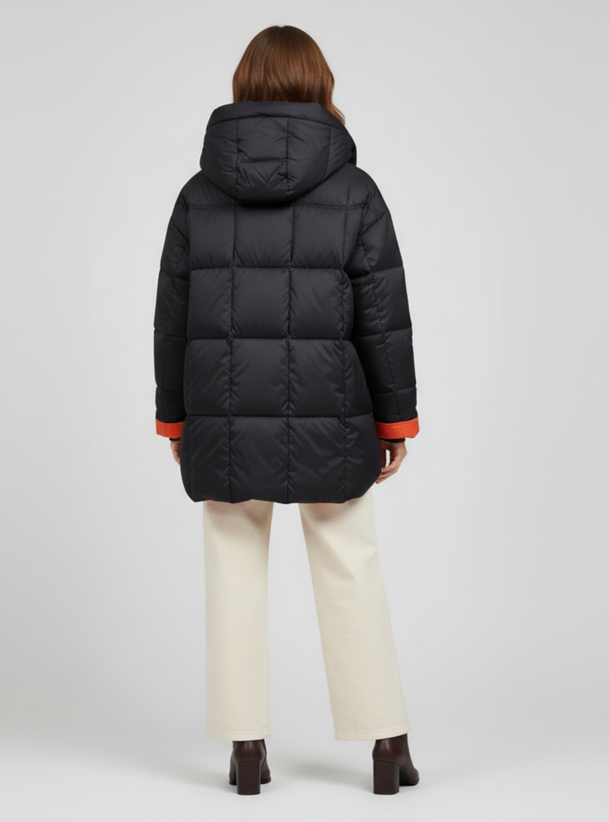 Person wearing a black puffer coat with red accents on a light gray background