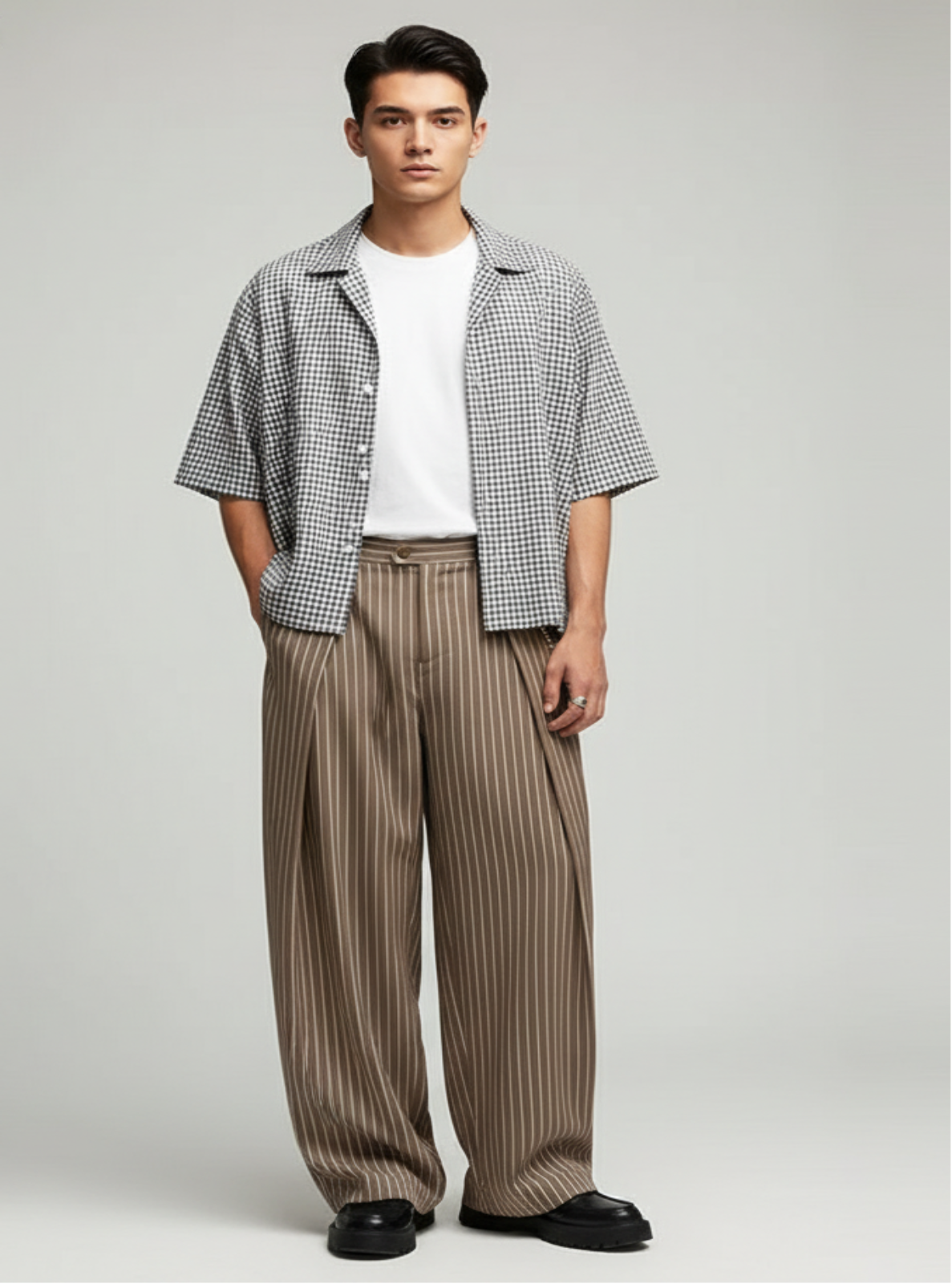 Man wearing a checkered shirt, white t-shirt, and wide-leg pants on a plain background