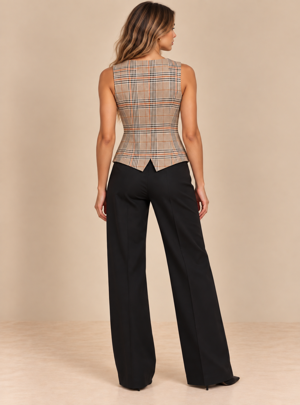 A woman shown from the back wearing a sleeveless plaid top with a structured waist and black wide-leg pants, standing against a plain beige studio backdrop.