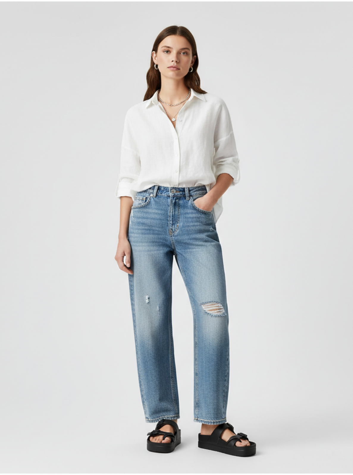 Woman wearing a white shirt and blue jeans on a light gray background