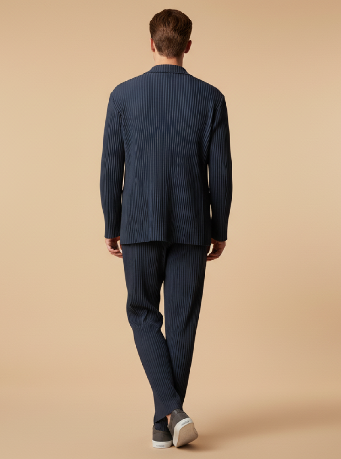 Man wearing a navy blue suit walking on a beige background