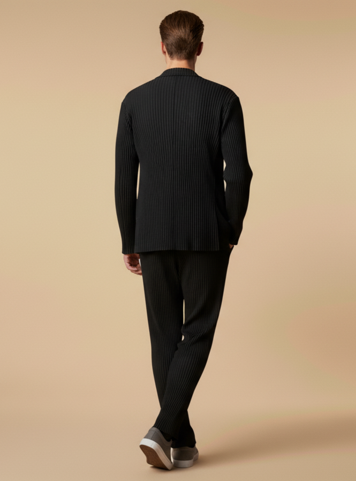 Man wearing a black suit walking on a beige background