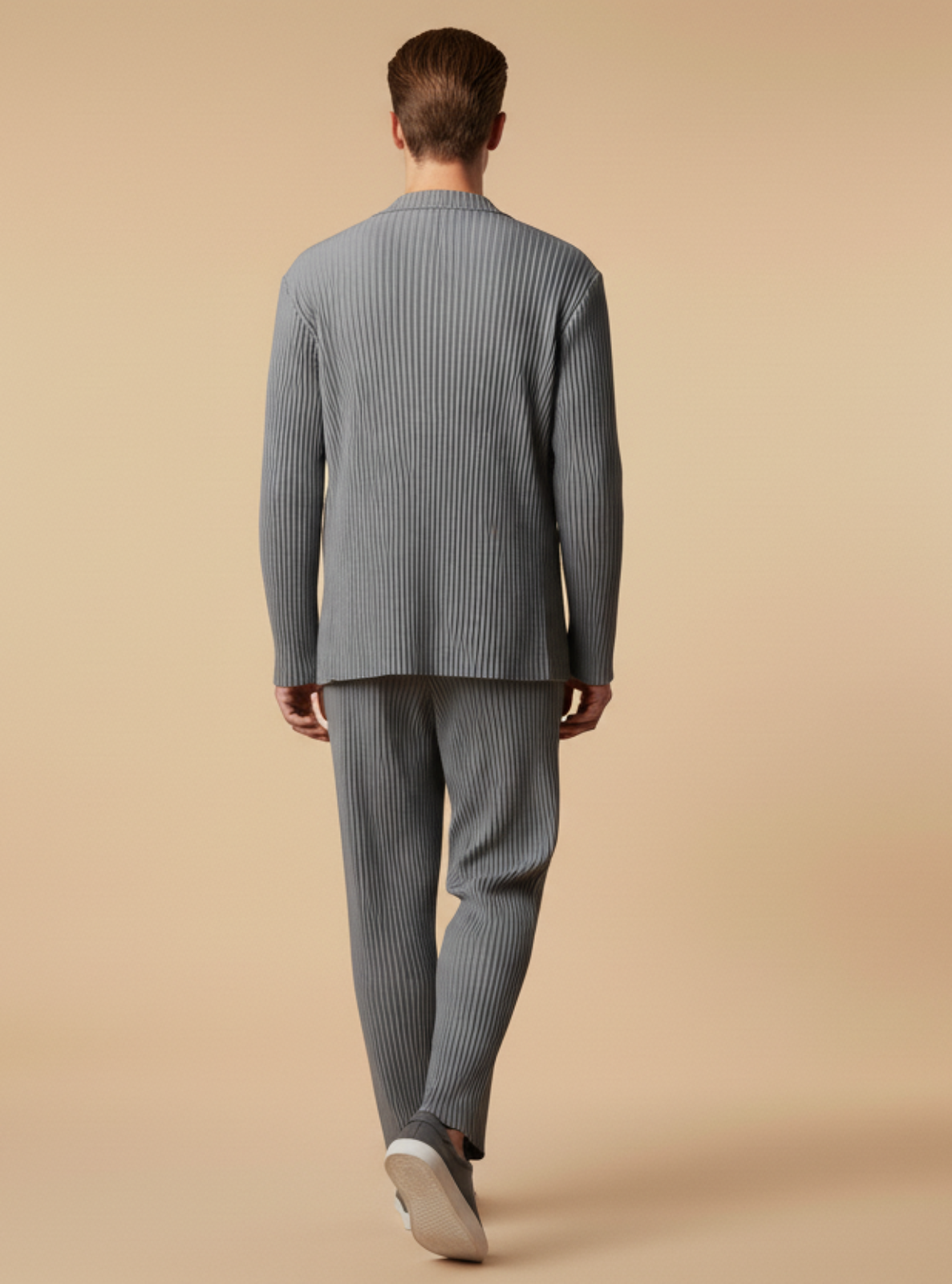 Man wearing a gray ribbed sweater and pants on a beige background