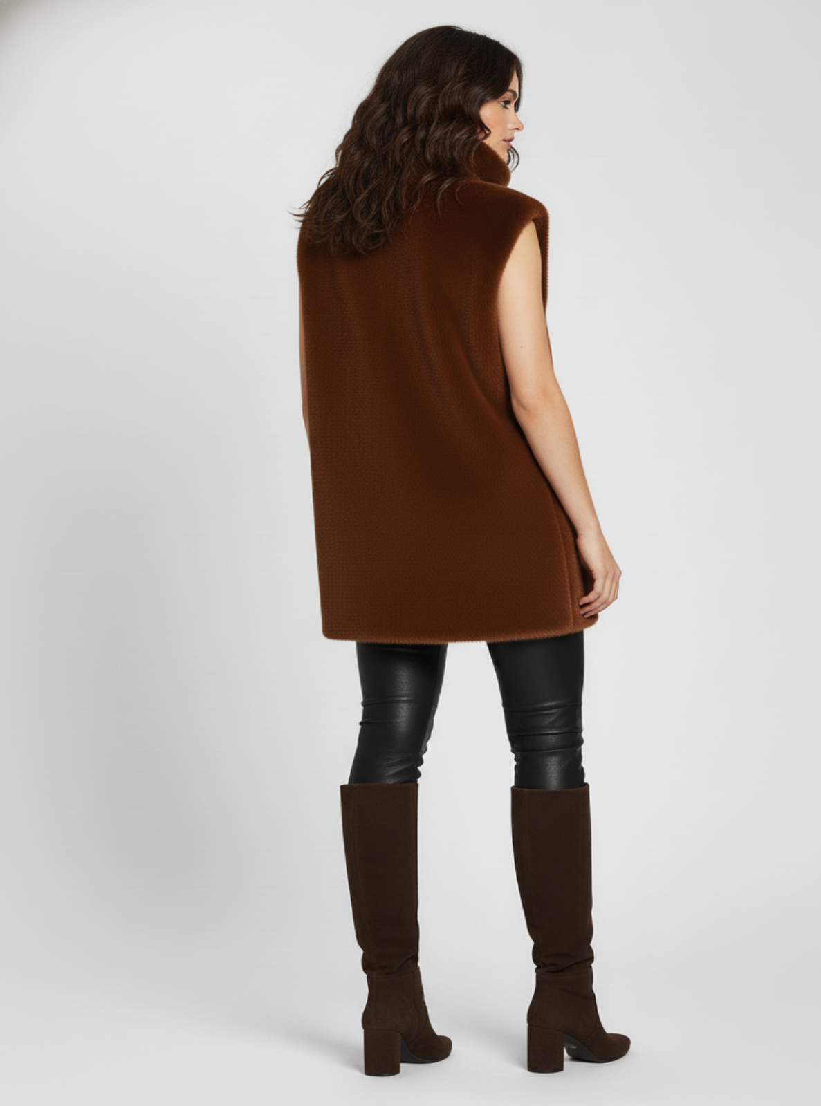 Woman wearing a brown sleeveless top and knee-high boots on a white background