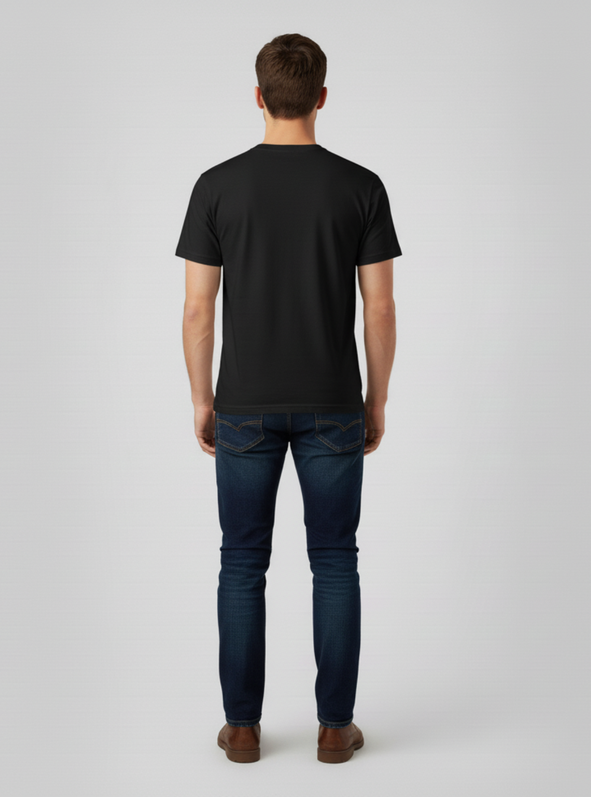 Man wearing a black t-shirt and dark jeans on a light gray background