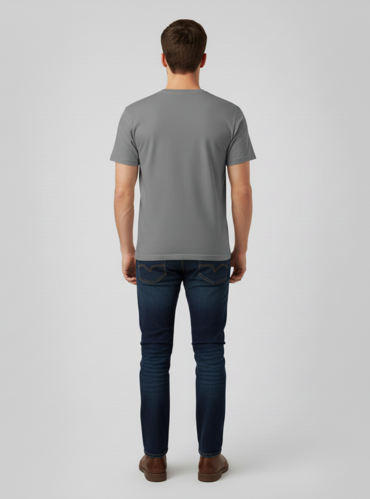 Man wearing a gray t-shirt and dark jeans on a light gray background