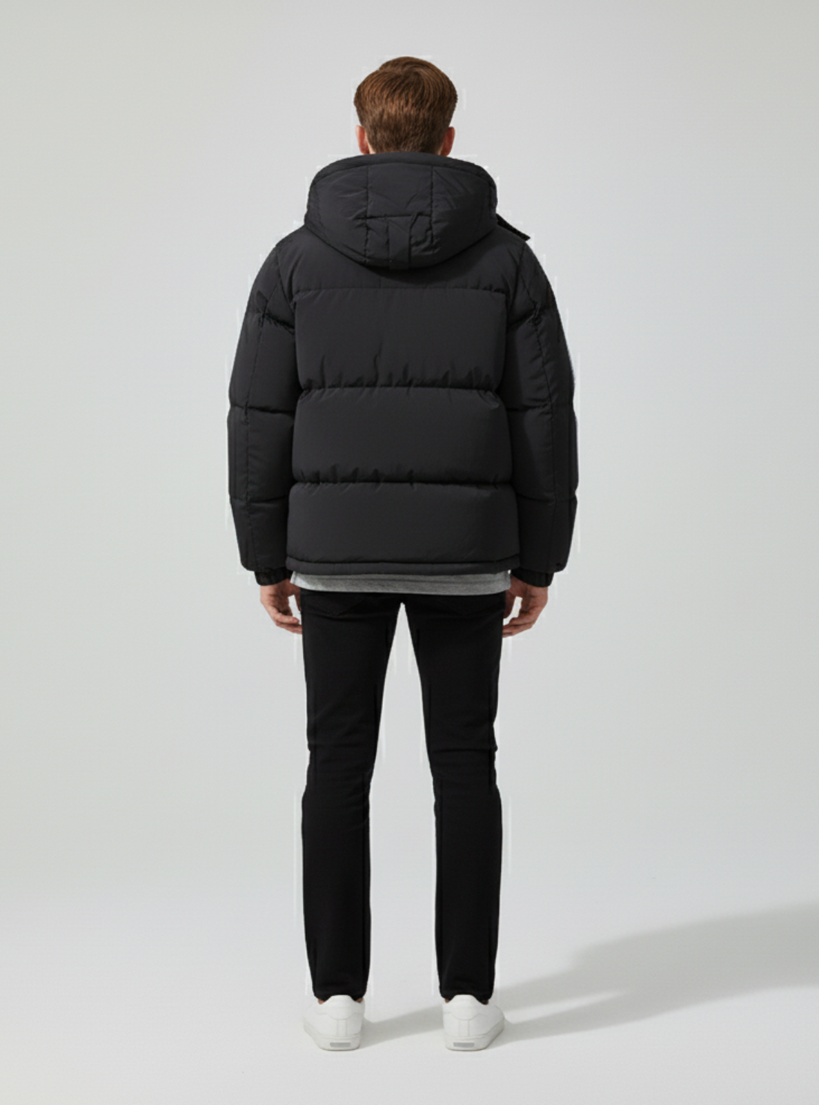 Person wearing a black puffer jacket on a white background