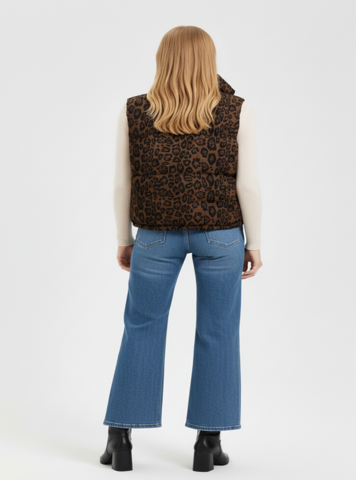 Person wearing a leopard print vest and blue jeans on a white background