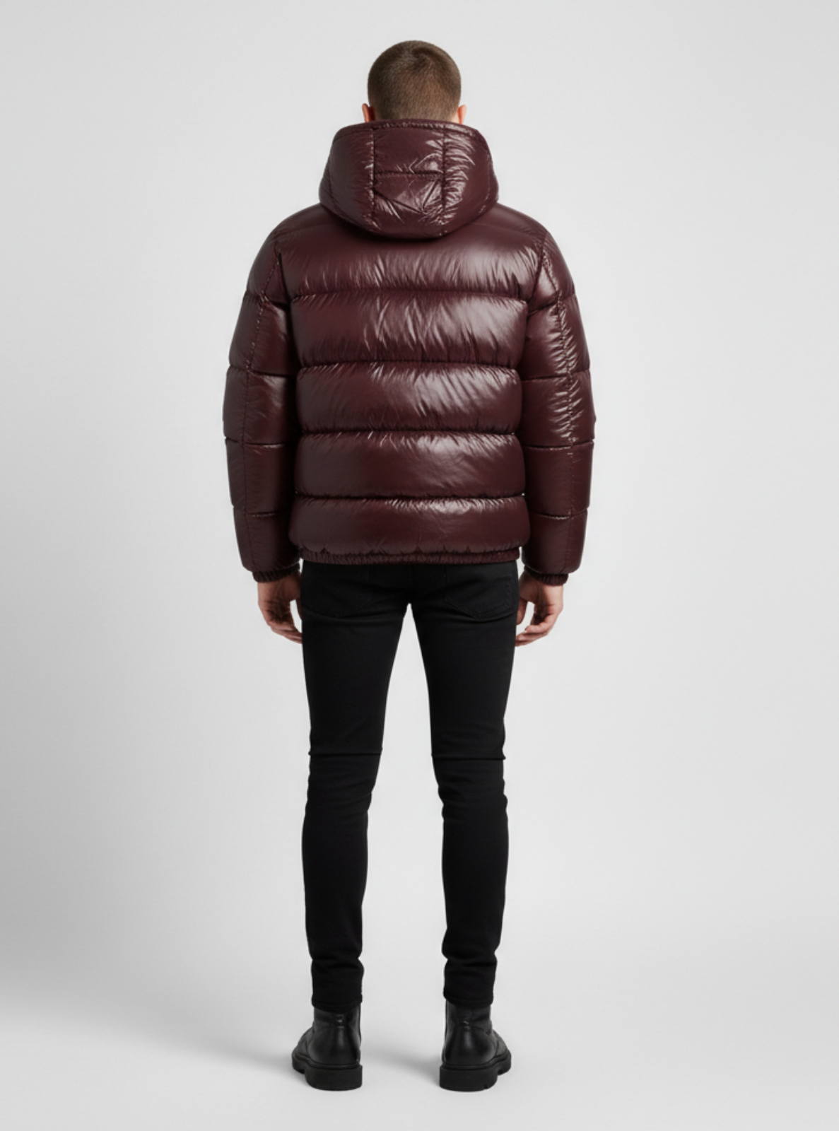 Man wearing a maroon puffer jacket on a light gray background