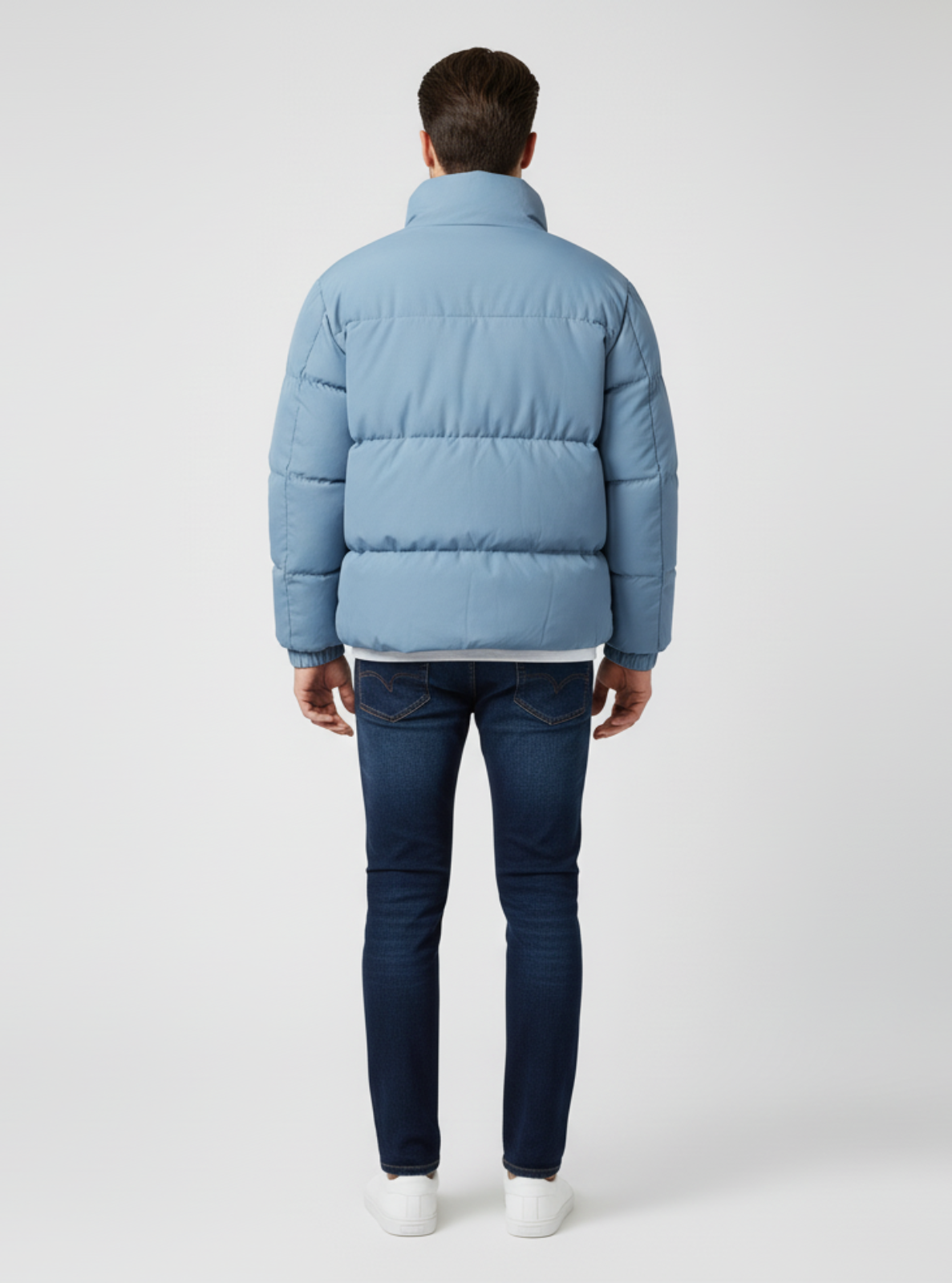 Person wearing a light blue puffer jacket and dark jeans on a white background
