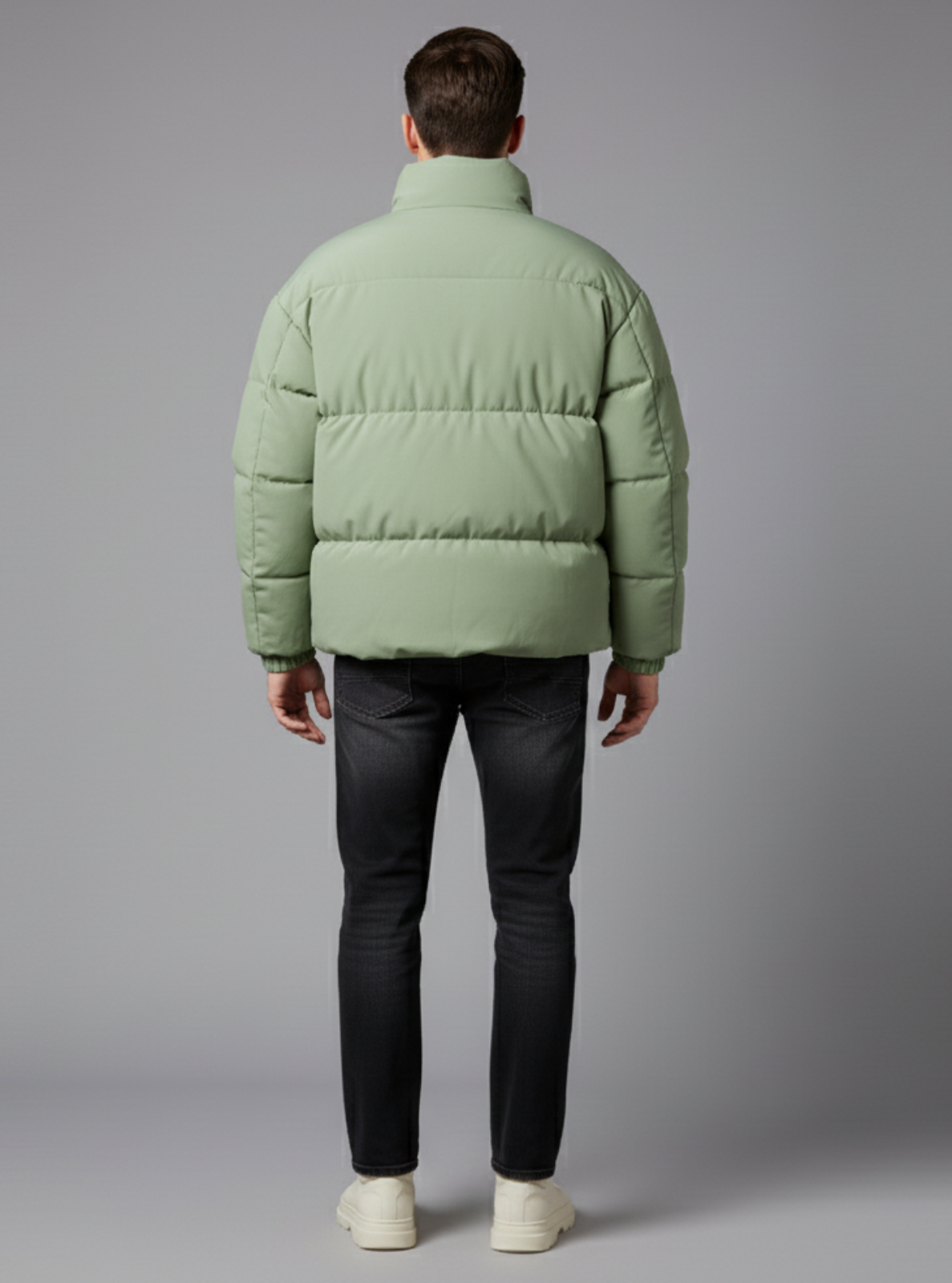 Person wearing a green puffer jacket on a gray background