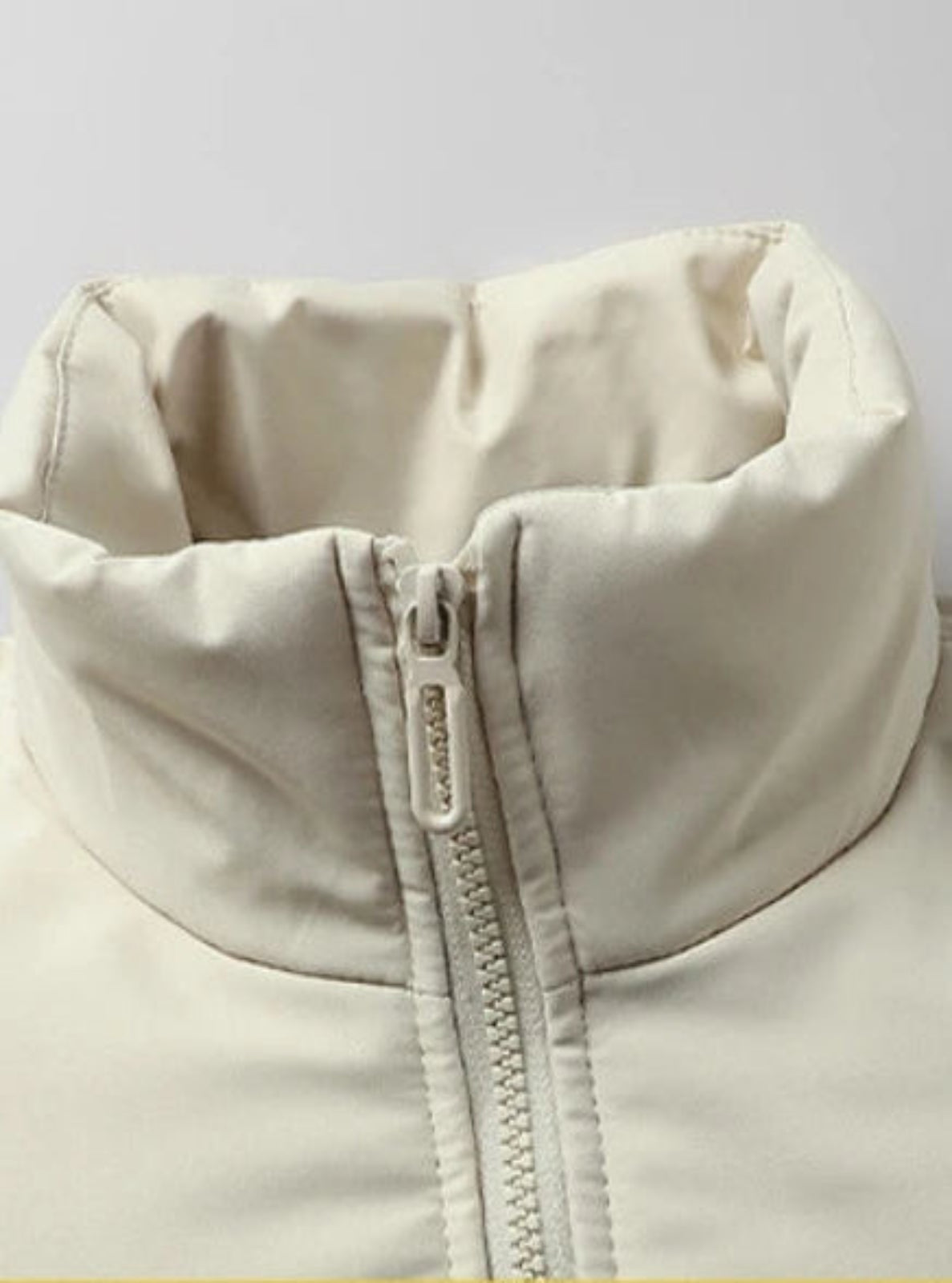 Close-up of a beige jacket with a zipper on a light gray background