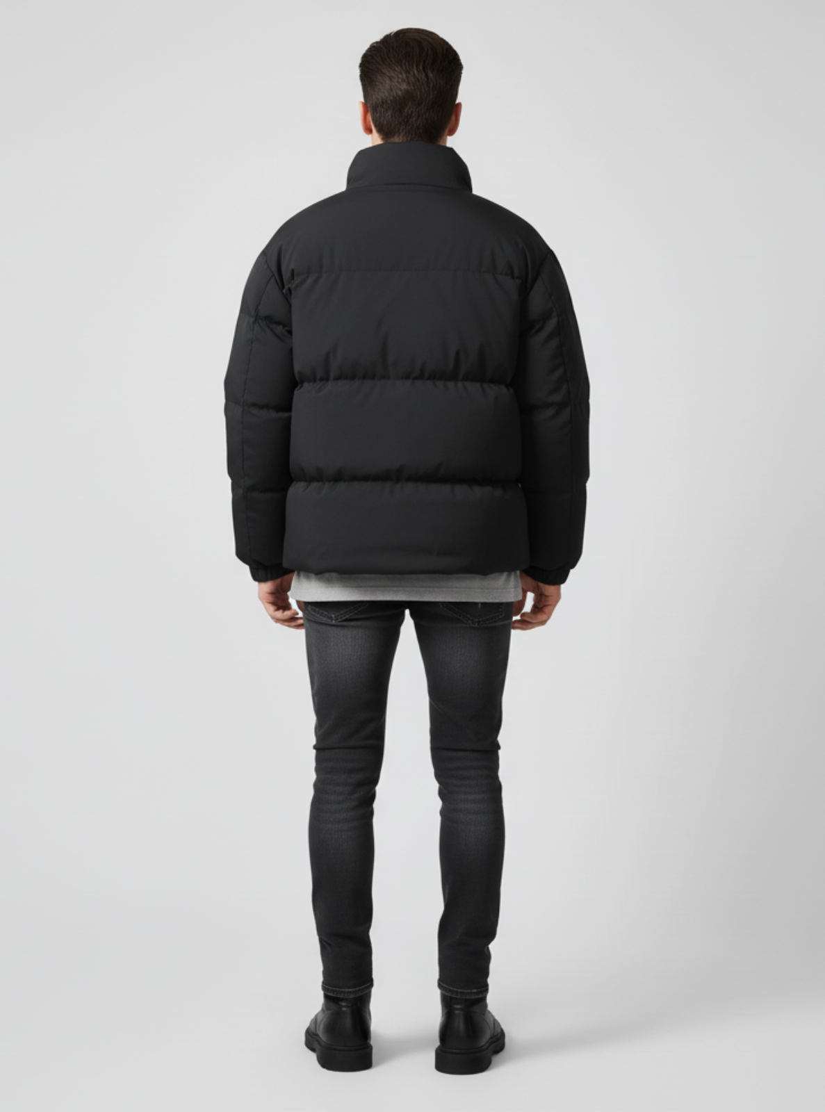 Person wearing a black puffer jacket on a light gray background