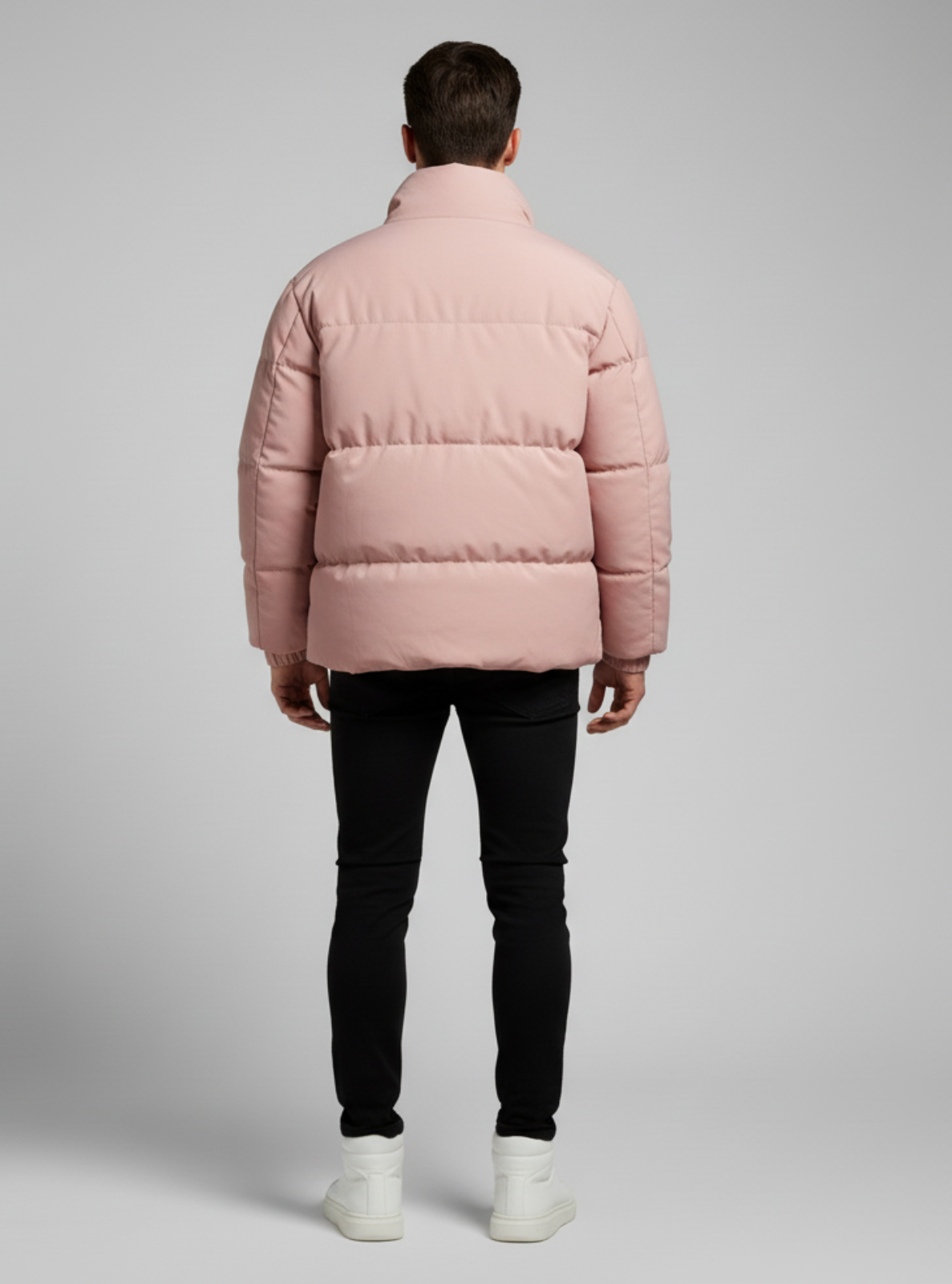 Person wearing a pink puffer jacket on a gray background