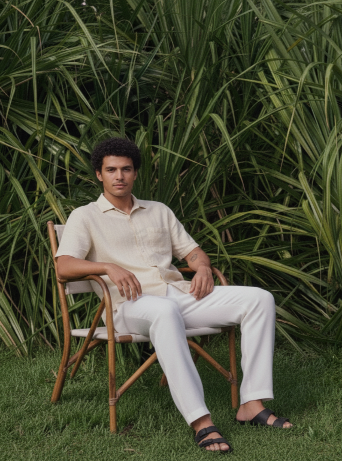 Man sitting in a chair surrounded by green foliage