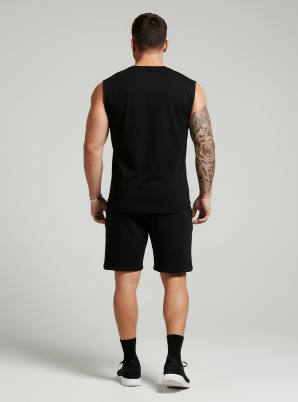 Man wearing a black sleeveless shirt and shorts on a plain background