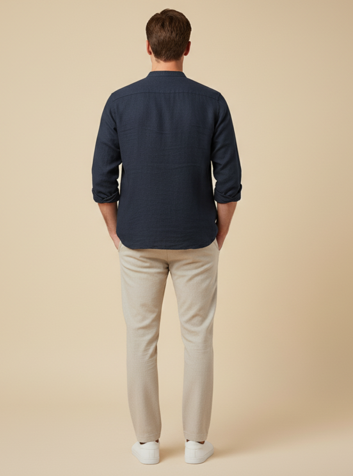 Man wearing a navy shirt and beige pants on a beige background