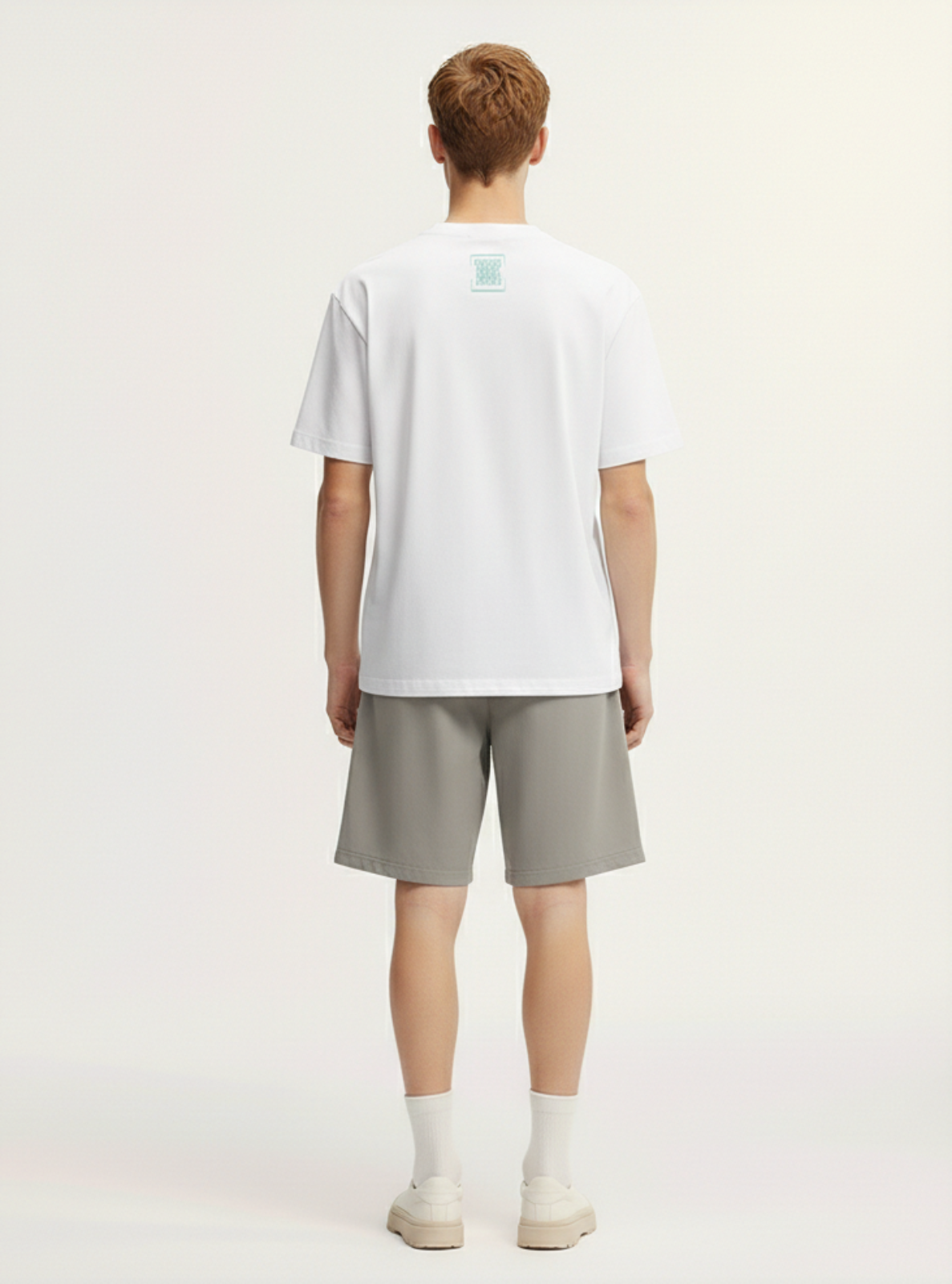 Person wearing a white t-shirt and gray shorts on a plain background