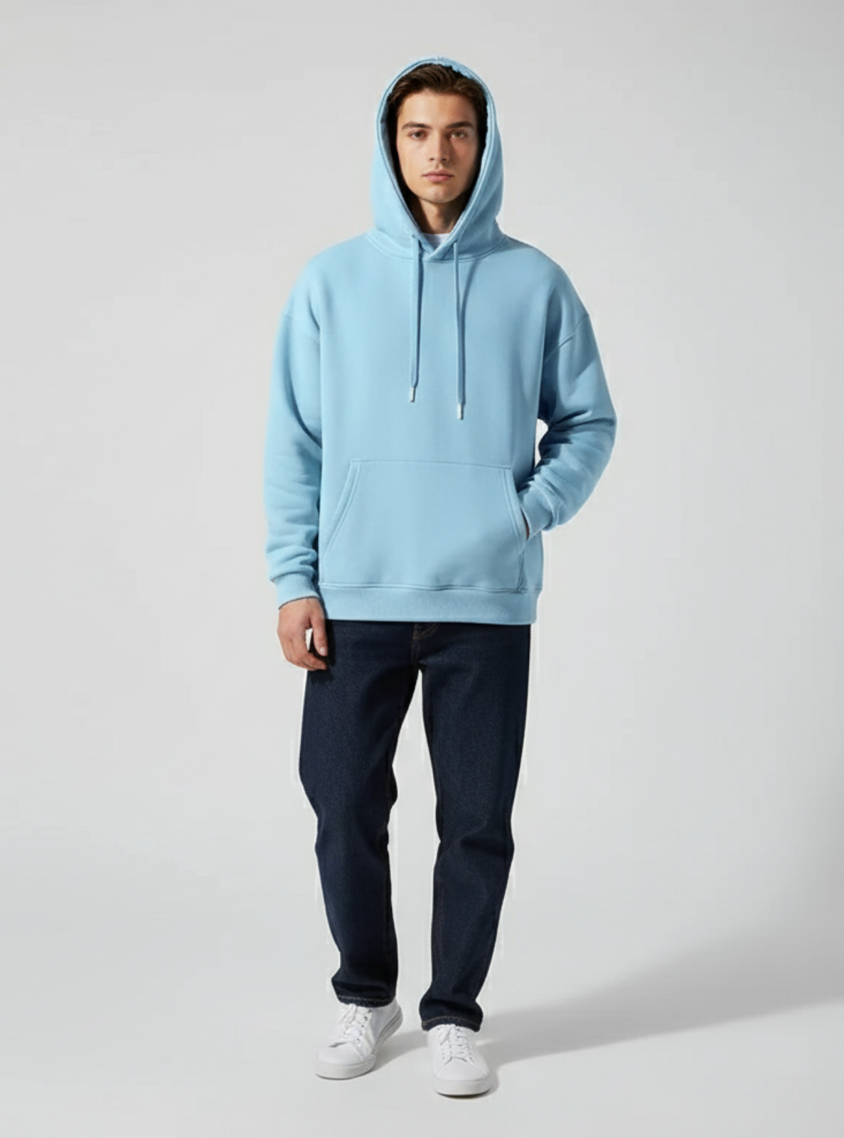 Person wearing a light blue hoodie and dark pants on a plain background