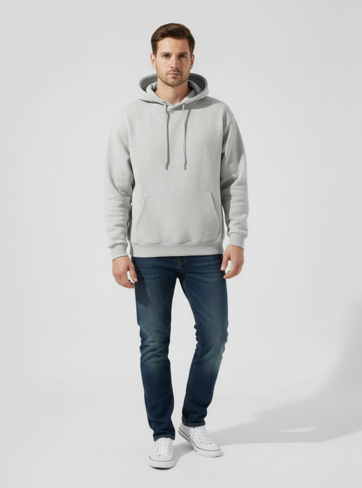 Man wearing a gray hoodie and blue jeans on a white background