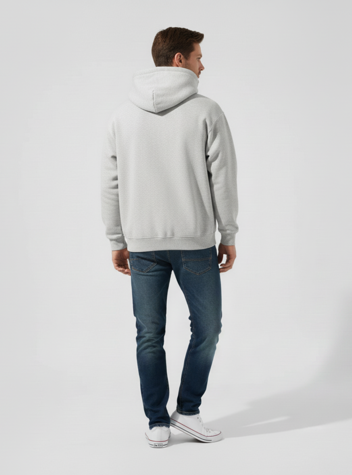 Person wearing a gray hoodie and blue jeans on a white background