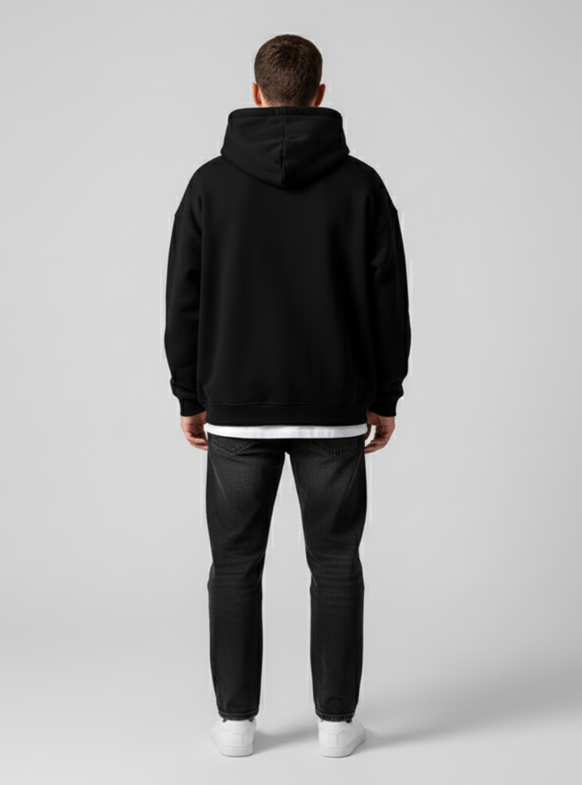 Person wearing a black hoodie and dark pants on a light gray background