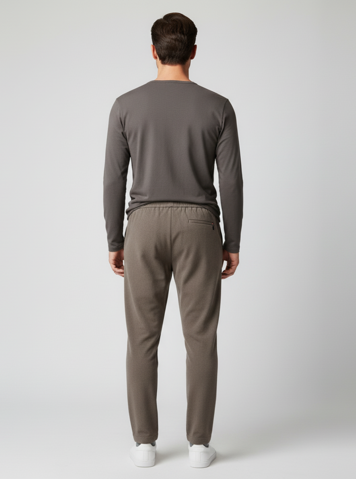 Man wearing a gray long-sleeve shirt and pants on a white background