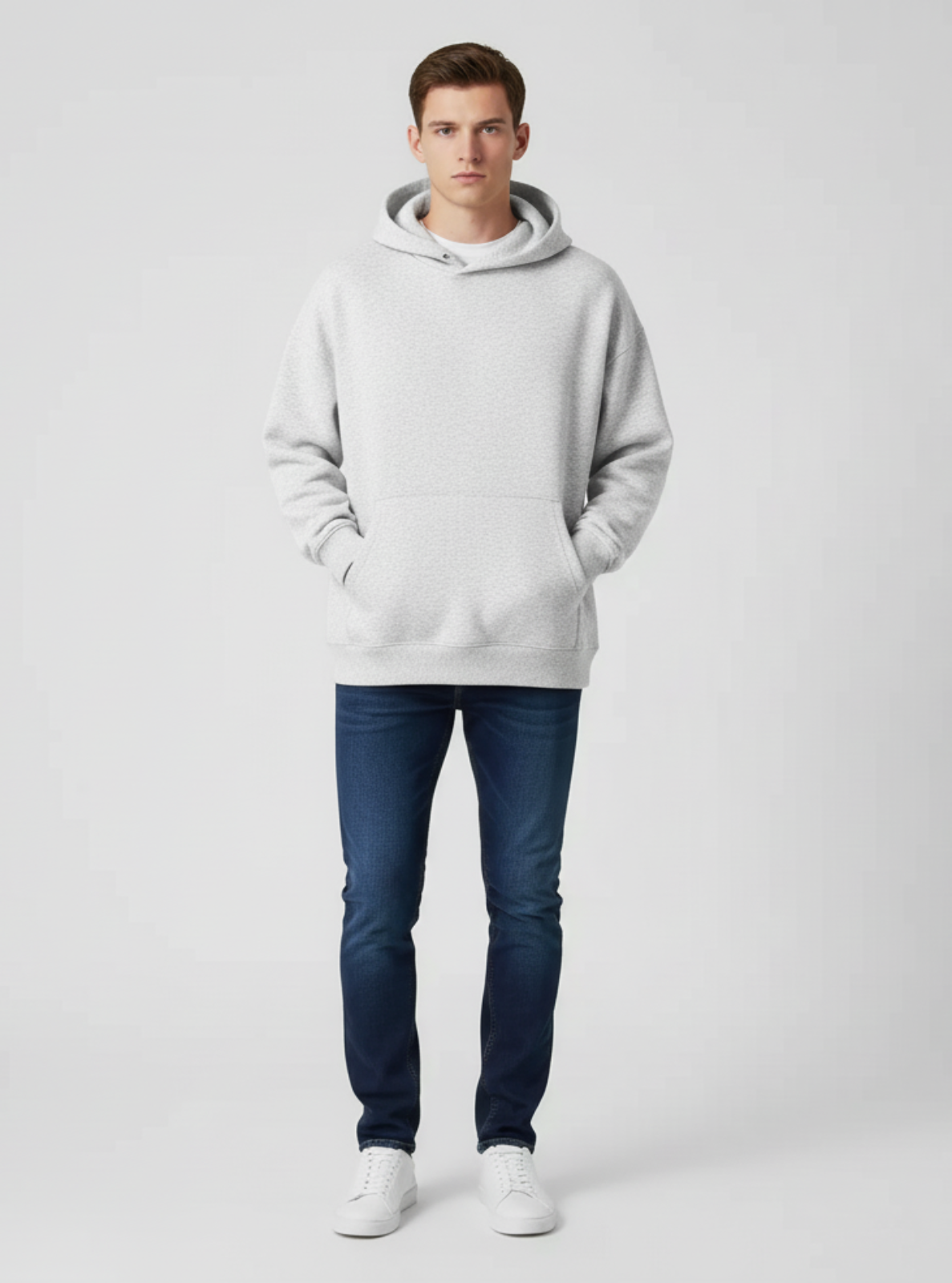 Man wearing a gray hoodie and blue jeans on a white background