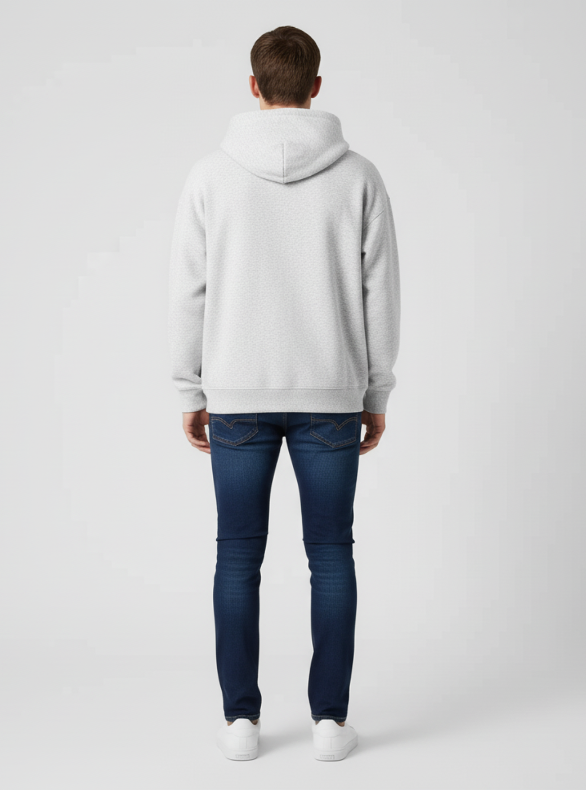 Person wearing a gray hoodie and blue jeans on a white background