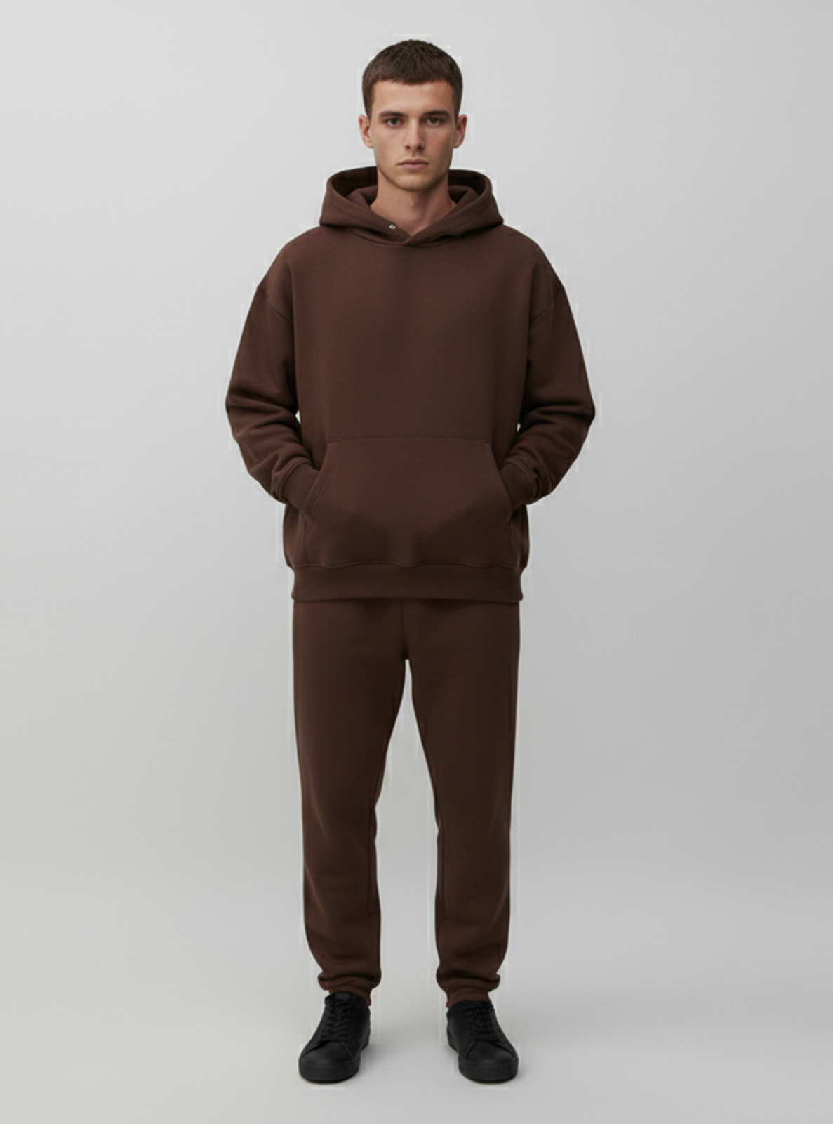 Man wearing a brown hoodie and pants on a white background