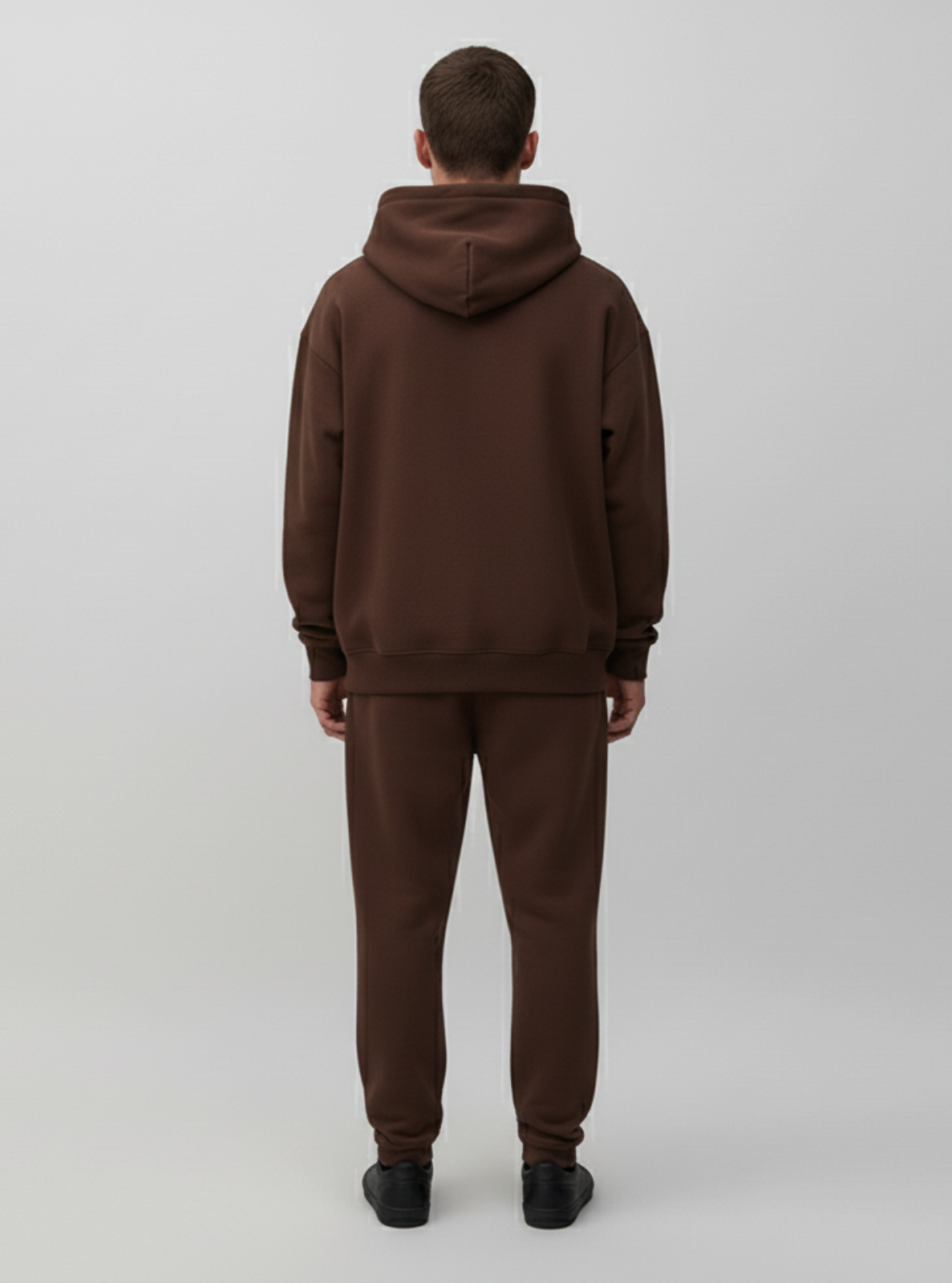 Person wearing a brown hoodie and pants set on a white background