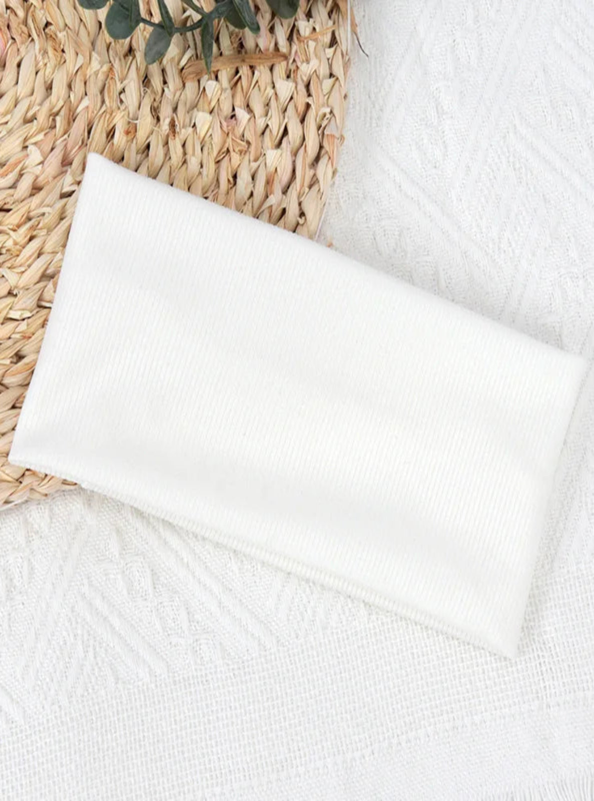 White towel on a textured surface with a woven basket in the background