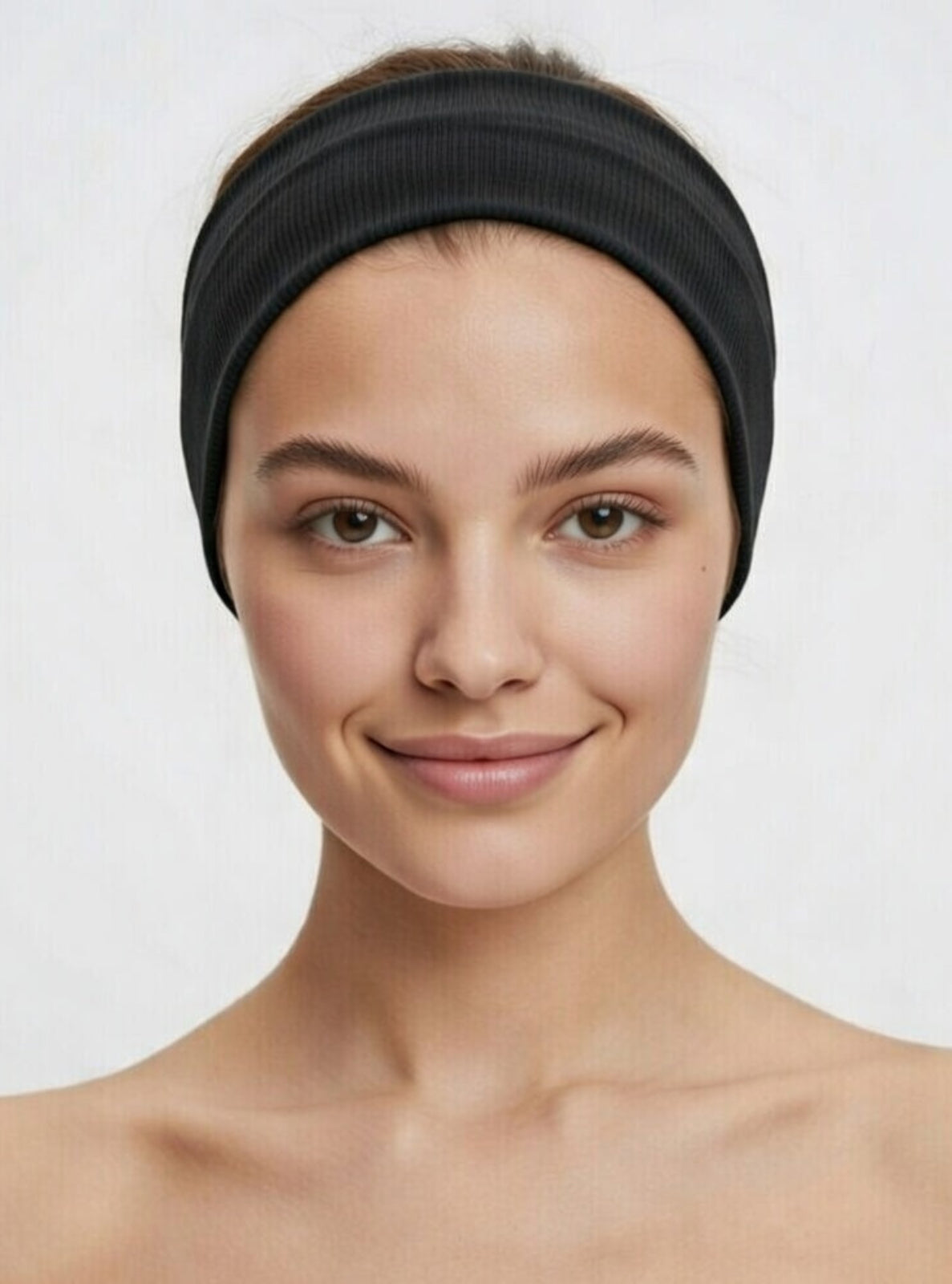 Woman wearing a black headband against a plain background