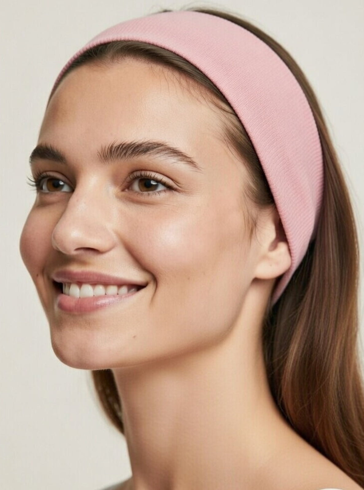 Woman wearing a pink headband against a plain background