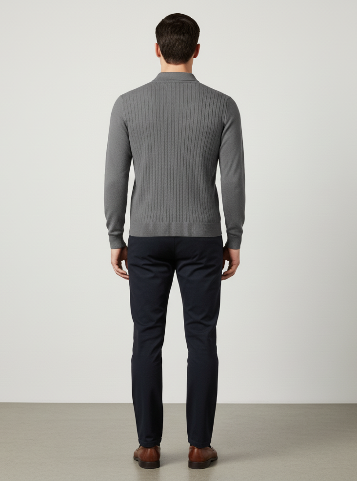 Man wearing a gray ribbed sweater and navy pants on a plain background