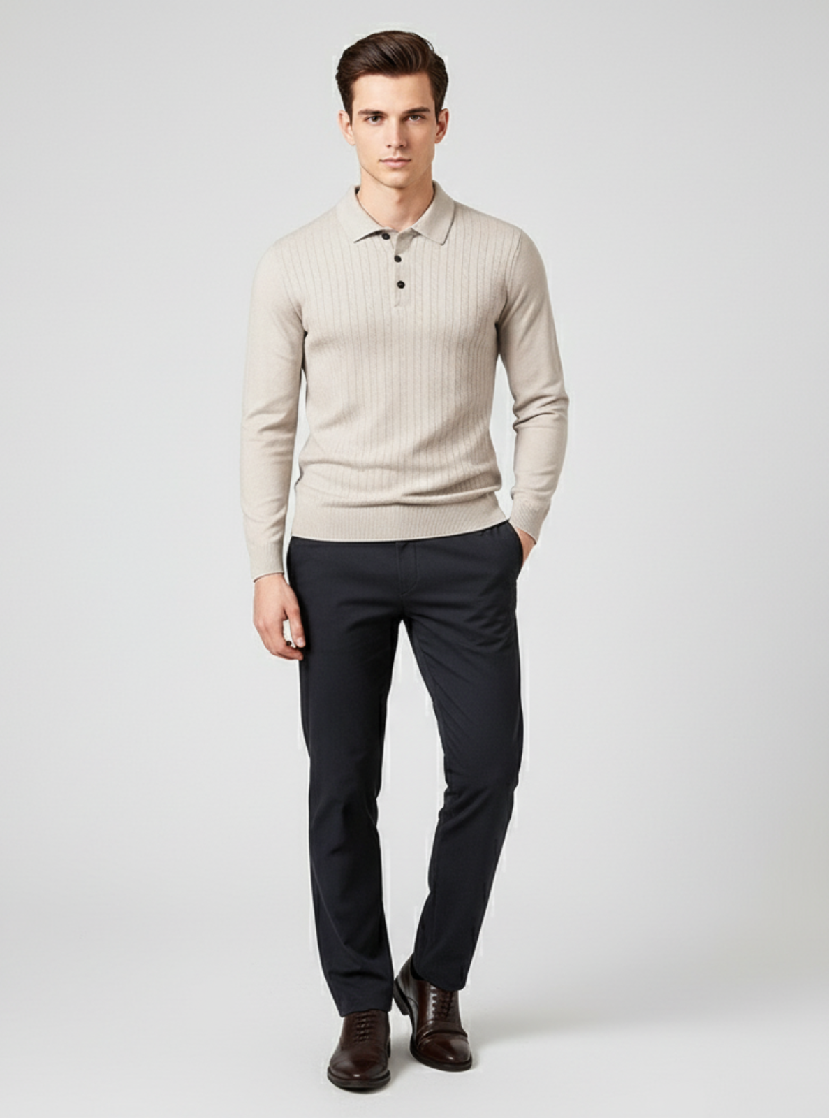 Man wearing a beige sweater and black pants on a light gray background